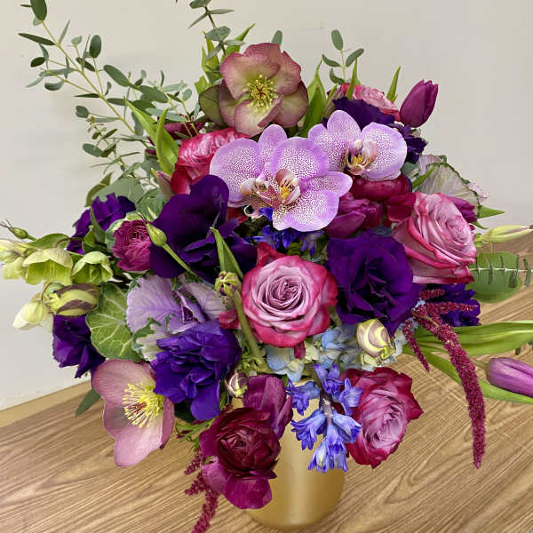 Bouquet of pink, purple, and lavender flowers in a gold vase