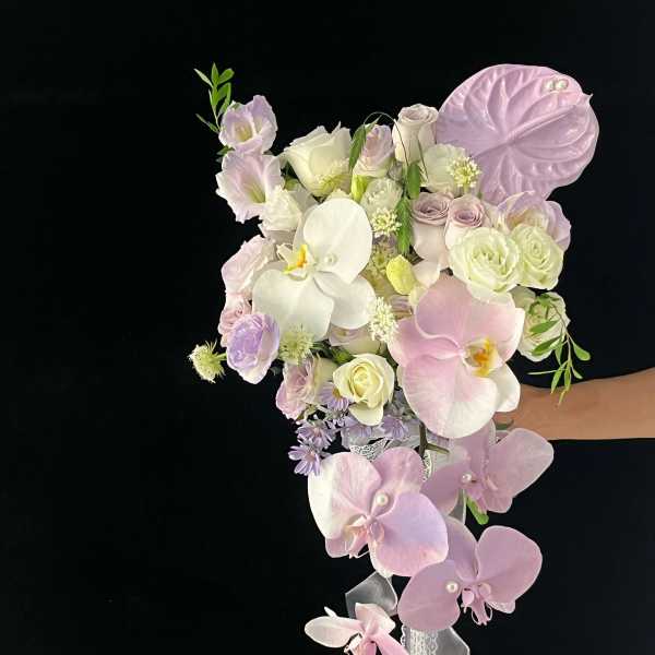 Pastel bouquet with orchids, roses, and calla lilies on a black background