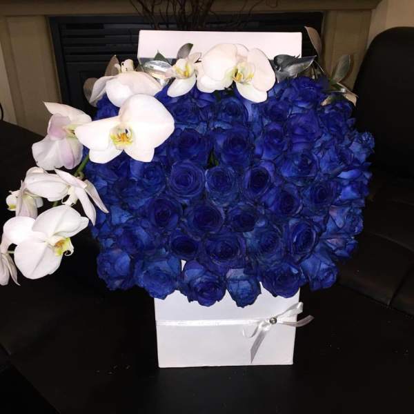 Blue rose arrangement with white orchids in a white box