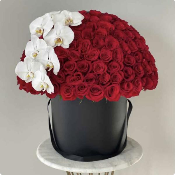 Red rose arrangement with white orchids in a black hatbox