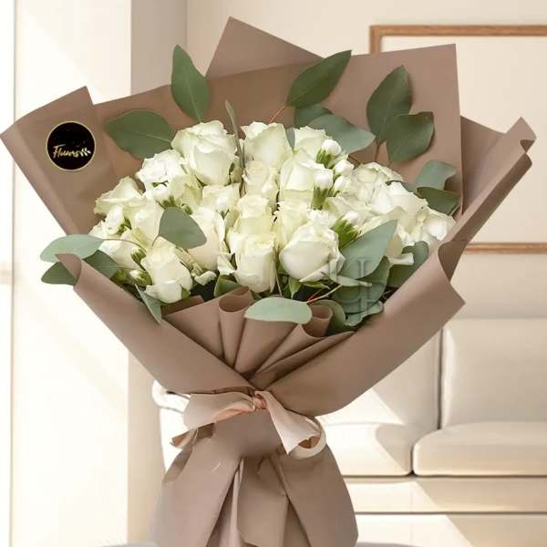 Bouquet of white roses wrapped in brown paper with eucalyptus