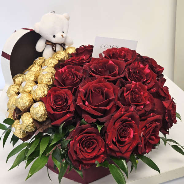 Red roses with gold-wrapped chocolates and a small teddy bear in a box