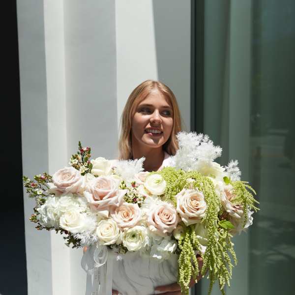 Woman holding a large bouquet of pale roses and white flowers
