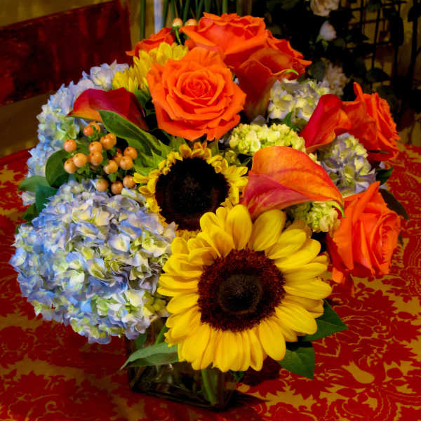 Colorful bouquet with roses, sunflowers, hydrangeas, and calla lilies in a vase