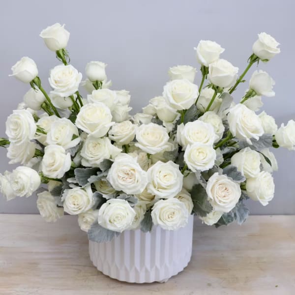 White rose arrangement in a ribbed white vase