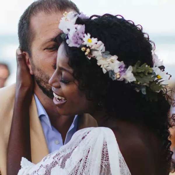 Bride wearing a floral crown embraces a man at an outdoor wedding