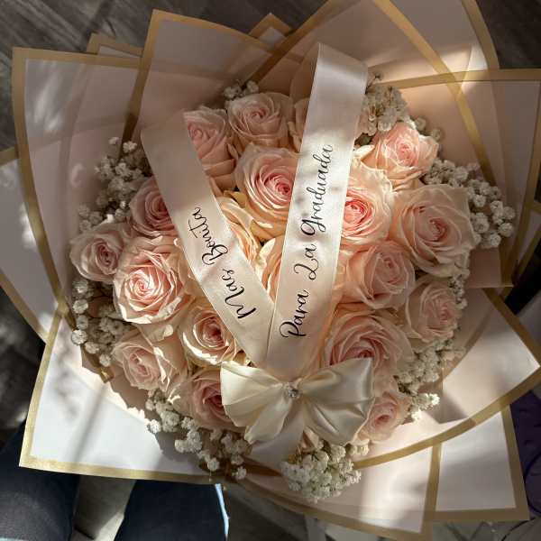 Bouquet of pale pink roses wrapped in cream paper with satin ribbons