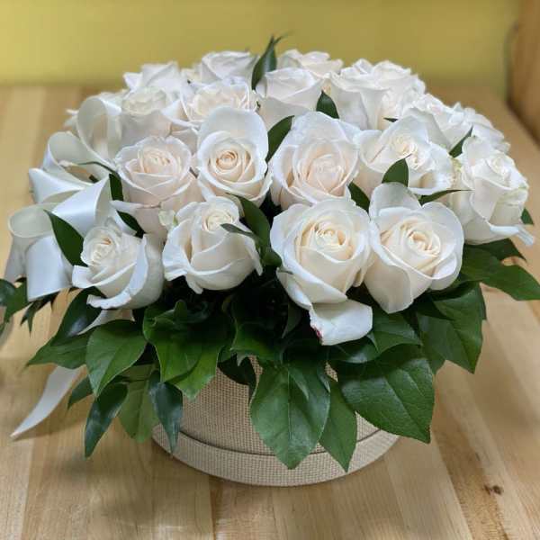 Round arrangement of white roses in a beige box with a white ribbon
