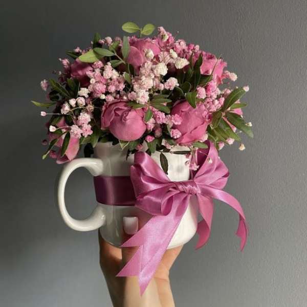 Pink rose bouquet in a white mug with a satin bow