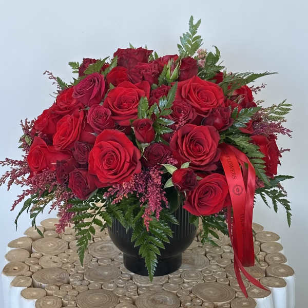 Red rose bouquet in a black vase with a red ribbon