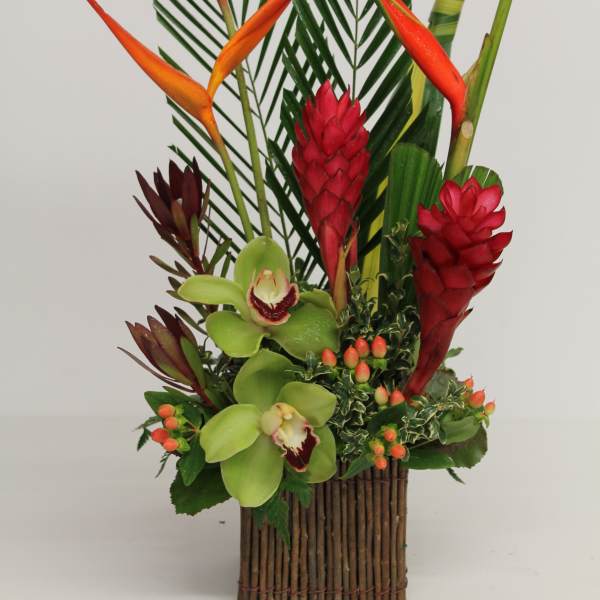 Tropical arrangement with orange heliconia and green orchids in a wooden container
