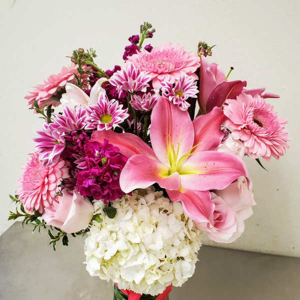 Pink mixed bouquet with lilies, roses, daisies, and white hydrangea in a glass vase