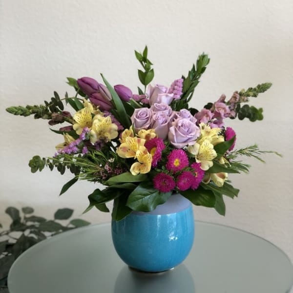 Mixed bouquet in a blue vase with lavender roses and yellow flowers