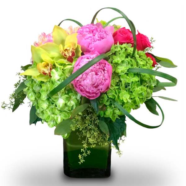Pink peonies, roses, and green hydrangeas in a square glass vase