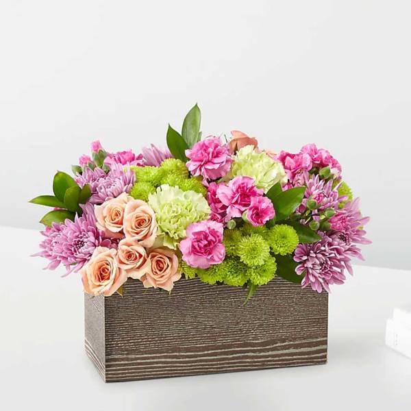 Mixed pink and peach flowers in a rectangular wooden box