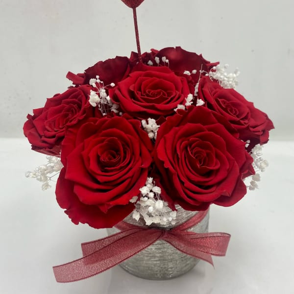 Red roses in a silver vase with a glitter heart pick