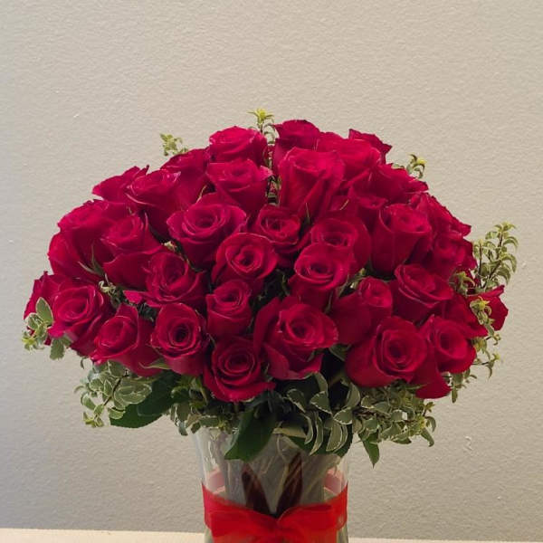 Bouquet of red roses in a clear glass vase with a red ribbon