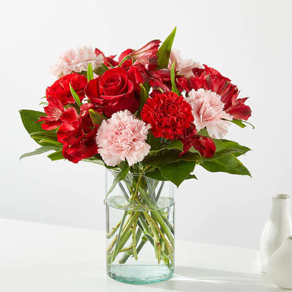 Bouquet of red roses and pink carnations in a clear glass vase