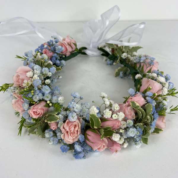 Floral wreath with pink roses and blue baby's breath tied with a white ribbon