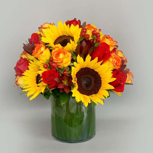 Bouquet of sunflowers and red roses in a glass vase