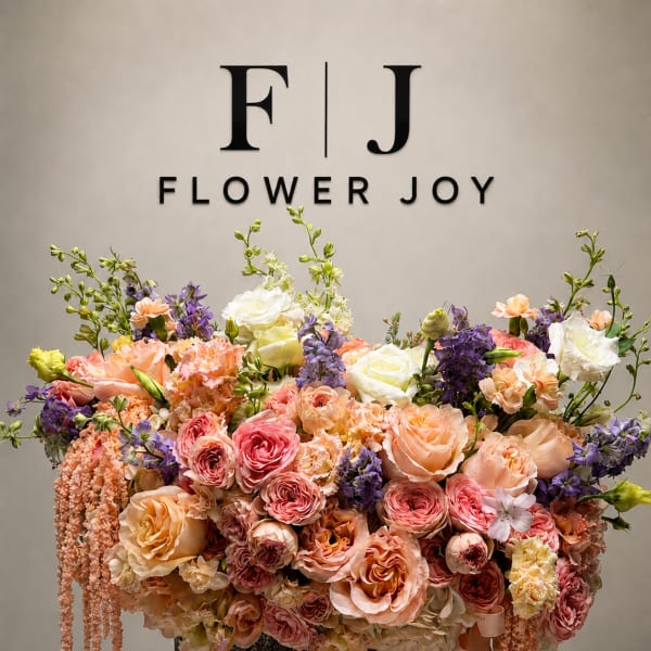Large pastel floral arrangement in a dark container with cascading blooms