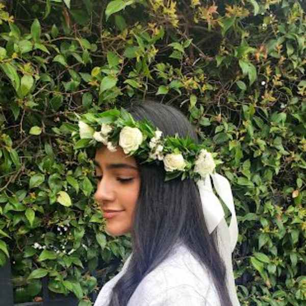 Woman wearing a white rose and greenery flower crown with trailing white ribbon