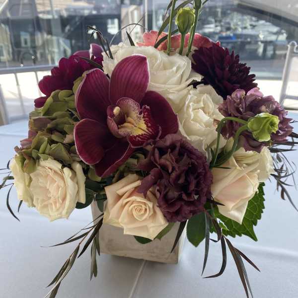 Bouquet of white and burgundy flowers in a square vase