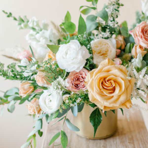 Peach and white roses arranged in a gold vase