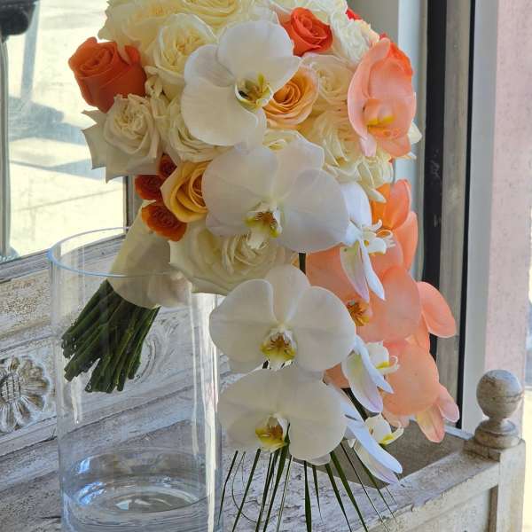 Bouquet of white and peach roses with white orchids in a clear glass vase