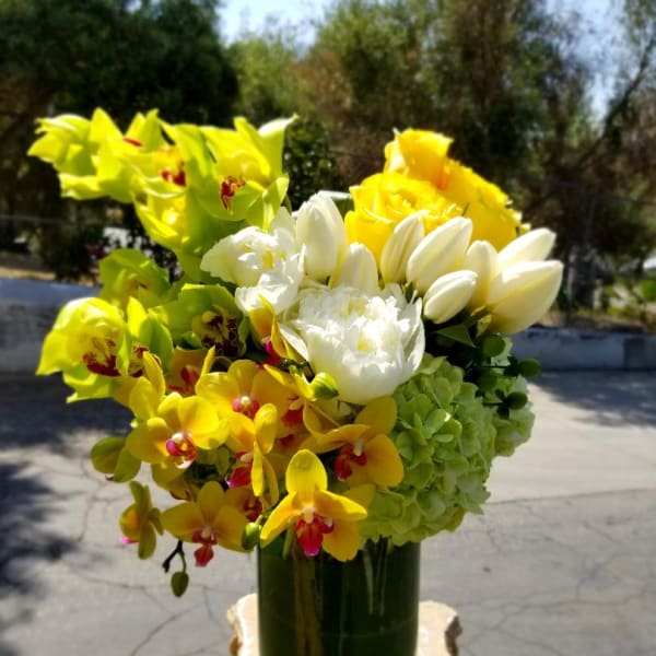 Bouquet of yellow and white flowers in a dark green vase