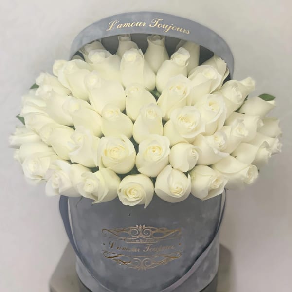 Round box of tightly packed white roses in a gray hatbox printed with L'amour Toujours