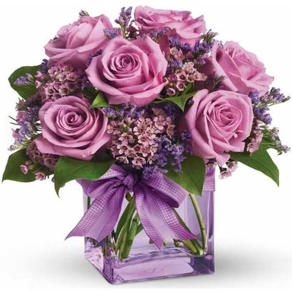 Pink roses in a purple glass vase with a ribbon bow