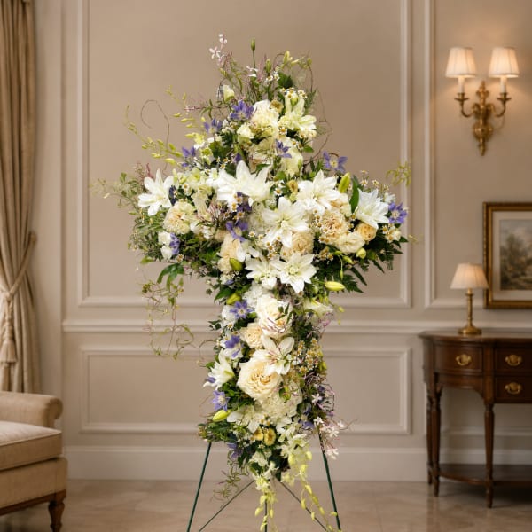 Tall standing floral cross with white and lavender flowers on a metal easel