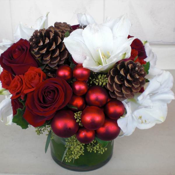 Red roses and white amaryllis with pinecones and red ornaments in a green vase