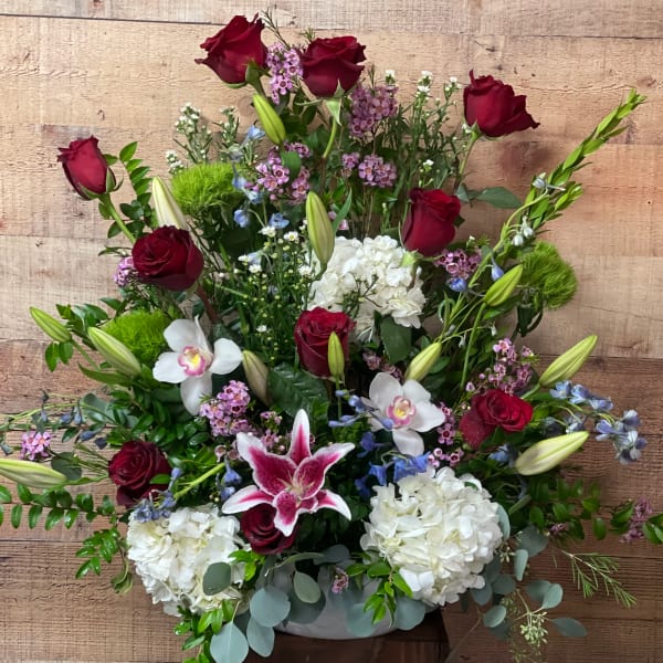 Mixed bouquet with red roses, white hydrangeas, and lilies in a low container