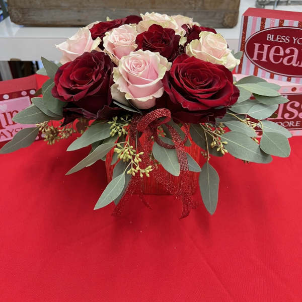 Red and blush roses arranged in a red gift box with ribbon