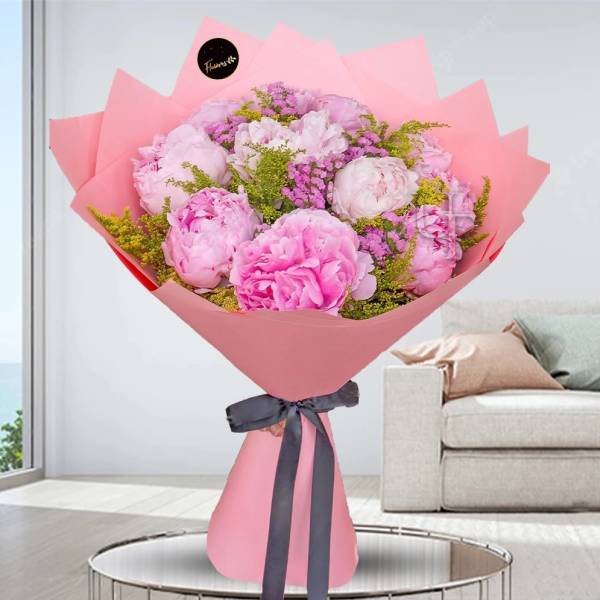 Pink bouquet of peonies wrapped in pink paper with a dark ribbon