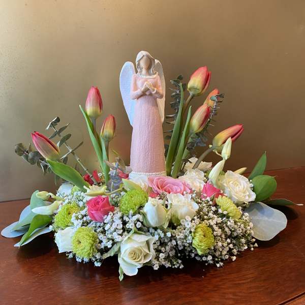 Pink tulips and roses arranged around a small angel figurine
