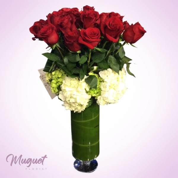 Red roses and white hydrangeas in a tall green vase