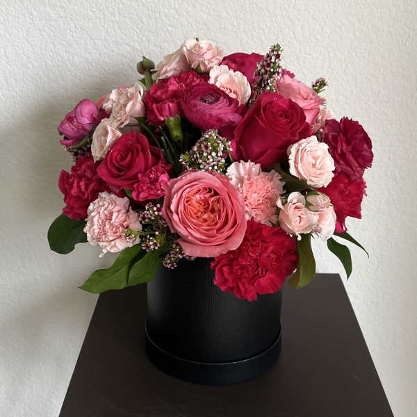 Pink and red rose and carnation arrangement in a black hat box