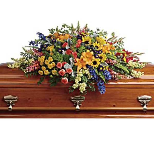 Colorful casket spray with mixed flowers on a wooden coffin