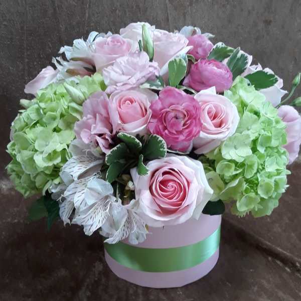 Pink roses and green hydrangeas arranged in a round box.