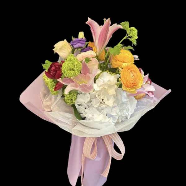 Pastel bouquet with lilies, hydrangea, and ranunculus wrapped in pink paper