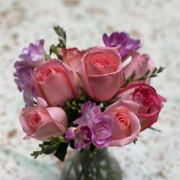Pink roses and purple flowers in a glass vase