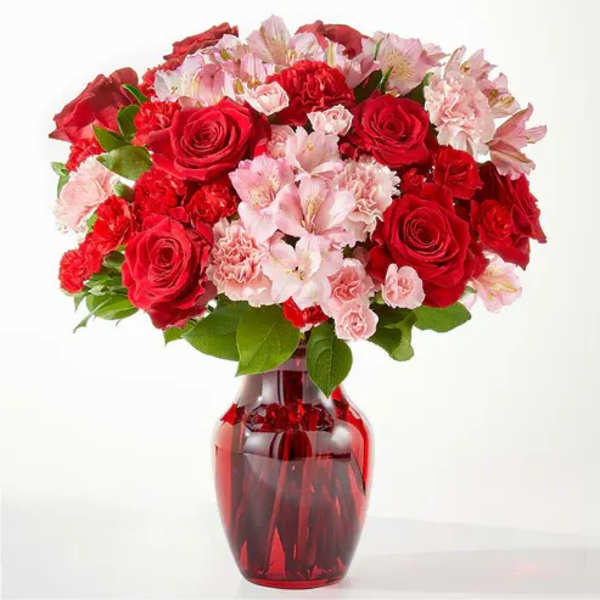 Red roses and pink carnations in a red glass vase