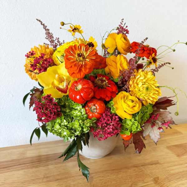 Bright mixed bouquet in a white vase with yellow, orange, and red flowers