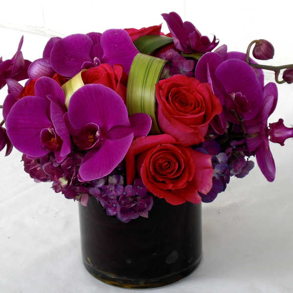 Purple orchids and red roses in a black vase