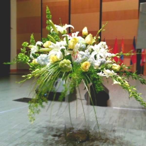 Large white and yellow floral arrangement in a tall stand
