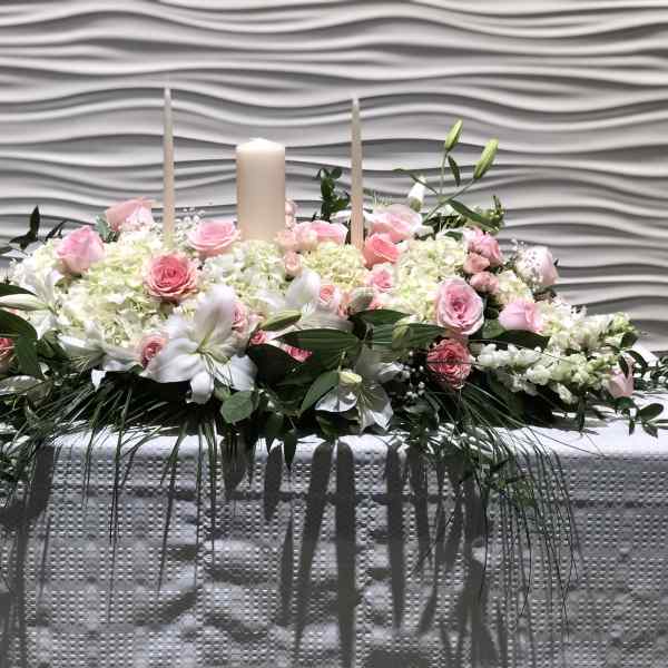 Pink and white floral centerpiece with candles on a table