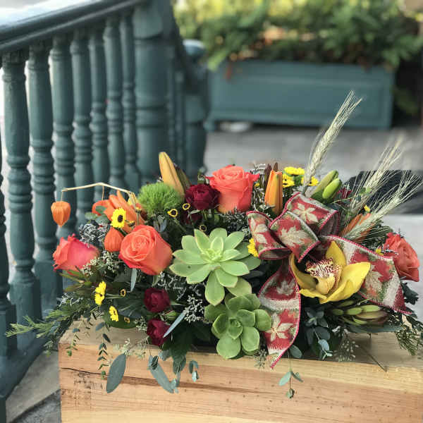 Colorful mixed floral arrangement with roses, orchids, and succulents in a wooden box